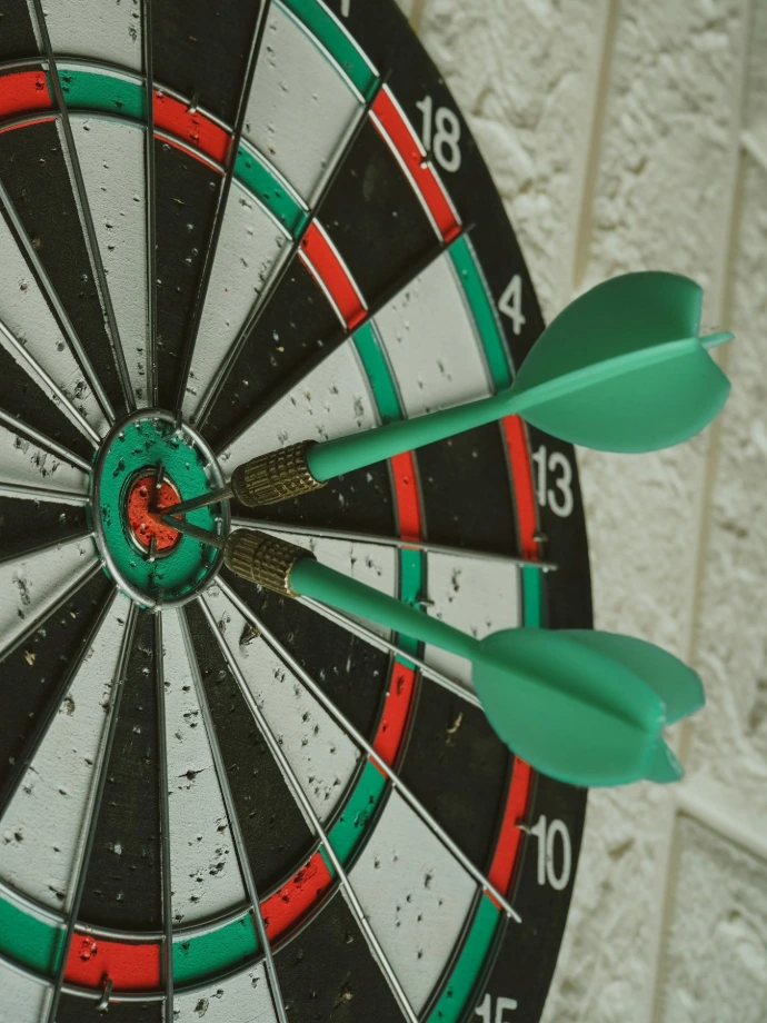 green darts hitting bullseye on dartboard
